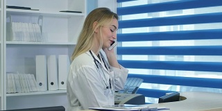 漂亮的护士在医院前台使用平板电脑和手机