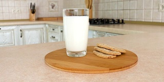 特写是一杯牛奶和健康脆脆的早餐饼干。以白色厨房为背景的旋转相机。Dolly-shot。
