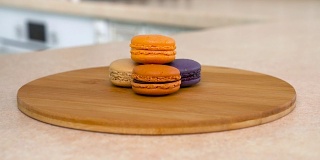 盘子里一堆五颜六色的杏仁饼干。以白色厨房为背景的旋转相机。Dolly-shot。