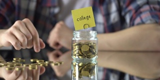大学字上面玻璃罐里装钱，储蓄教育投资观念