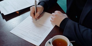 一个成功的商人正坐在餐厅的办公桌前签合同