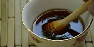 用手从杯子里取出木质的蜂蜜勺