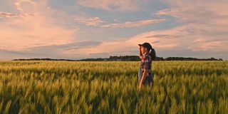 年轻的少女走在宁静的，田园诗般的，乡村绿色麦田里，慢镜头