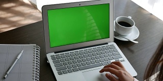 一个女人在家里看着绿色屏幕的笔记本电脑