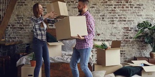 一对有吸引力的夫妇在他们的新房子的卧室里搬箱子，男人在搬运东西，而他的女朋友在帮助他。人员与搬迁理念。