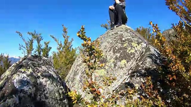 一位年轻女子独自坐在一块岩石上，观察法国的比利牛斯山脉