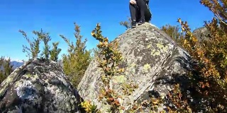 一位年轻女子独自坐在一块岩石上，观察法国的比利牛斯山脉