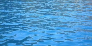 游泳池或海中的蓝色清澈的水潭。美丽的水纹理背景。特写慢动作