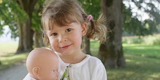 肖像:顽皮的女儿一边抱着她的玩具，一边对着镜头微笑。