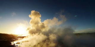 冰岛间歇泉喷发。冬天的冷色，阳光透过蒸汽照射
