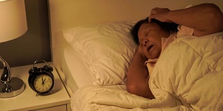 患有失眠症的老妇人正试图晚上在床上睡觉