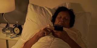一个老女人晚上在床上玩手机