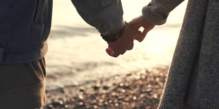近距离拍摄的男人和女人的手，夫妇俩正站在海边