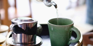 用茶壶将茶倒入绿咖啡杯的慢镜头