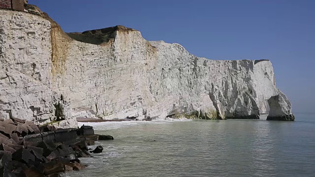 英国东苏塞克斯海福德附近的白色白垩峭壁，海浪拍打着悬崖和蓝色的大海和天空