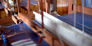 近距离的工人在木制编织线机制作传统泰国纺织丝绸制造