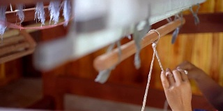 近距离的工人在木制编织线机制作传统泰国纺织丝绸制造