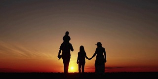 夕阳下幸福的一家人散步的剪影