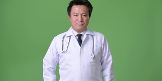 成熟的日本男人医生反对绿色背景
