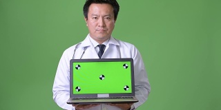 成熟的日本男人医生反对绿色背景