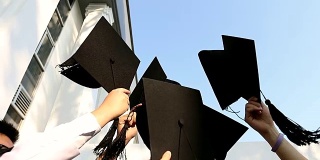快乐的学生们穿着长袍在空中展示着学位帽。教育、毕业与人观念。