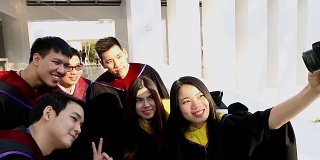 一群兴高采烈的留学生穿着学士服，在户外用小相机自拍。教育、毕业、技术、人的观念。