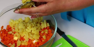 俄罗斯肉沙拉配蔬菜和蛋黄酱。一个女人正在切煮土豆。