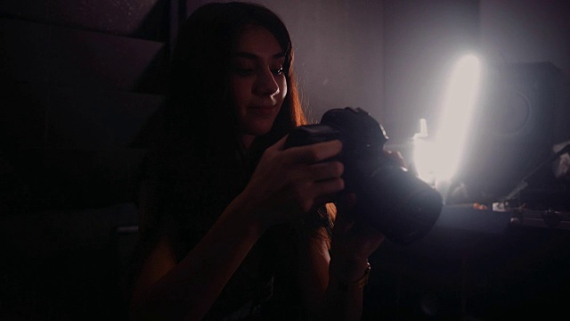 年轻的职业女摄影师在摄影棚里用灯光拍照