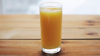 橙汁倒进木桌上的玻璃杯里视频素材模板下载