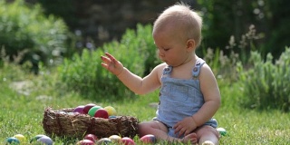 可爱的孩子，在盛开的花园里玩着小兔子和复活节彩蛋，春天。男孩玩兔子，找鸡蛋过节