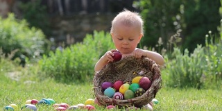 可爱的孩子，在盛开的花园里玩着小兔子和复活节彩蛋，春天。男孩玩兔子，找鸡蛋过节