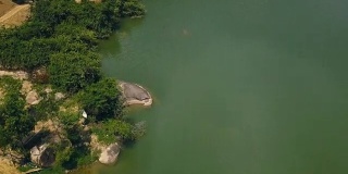 绿色的水和岸上的大石头美丽的湖空中拍摄无人机。公路沿河与岩石海岸无人机视图