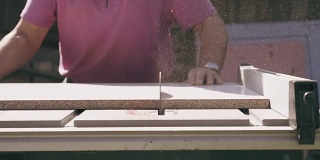 工人正在做细木工在圆锯近景。人用旋转的刀片切割木板，然后走开。慢动作