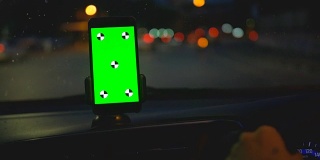 司机在车上使用绿色屏幕的智能手机
