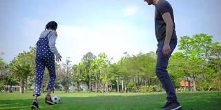 小女孩和爸爸一起踢足球