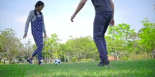 小女孩和爸爸一起踢足球
