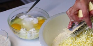 一位妇女在混合配料，准备做大理石蛋糕。用磨粉器把黄油磨成面团。桌子旁边是其他的食材。