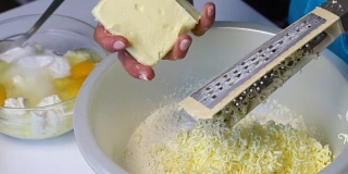 一位妇女在混合配料，准备做大理石蛋糕。用磨粉器把黄油磨成面团。
