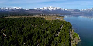 春天的太浩湖，加利福尼亚茂密的森林和葱郁的海湾沿着南岸与雪山景观的背景