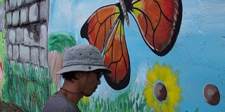壁画画家在学校的墙上画蝴蝶。