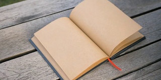 女人的手慢慢地翻着一本干净的书。一个米黄色的笔记本。戒指戴在手指上
