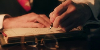 40多岁的商人用钢笔在公司账本上写字