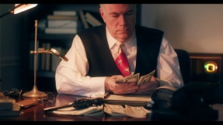 一个20世纪40年代黑帮风格的会计师在数钱，然后用钢笔在分类帐上记账。视频素材模板下载