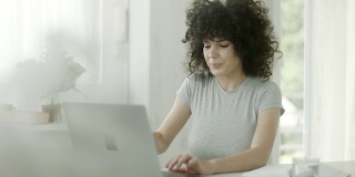 年轻女子端着咖啡在办公室使用笔记本电脑