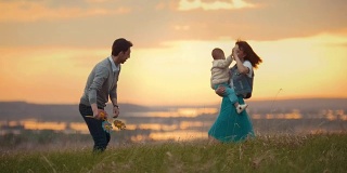 年轻的夫妇和一个孩子跳舞，在自然和日落的乐趣