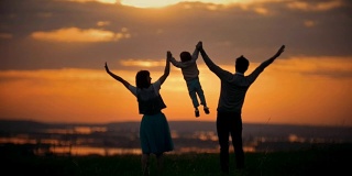 全家手牵爸爸妈妈在空中抚养宝宝，一家人欢天喜地，橘红色的夕阳，夏日