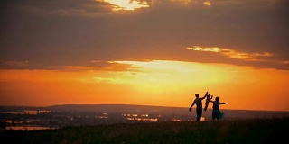 橘黄色的夕阳下一家人与一个小男孩手牵着手休息在大自然中