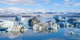 4k时间移动的云与蓝色冰山漂浮在Jokulsarlon冰湖，冰岛