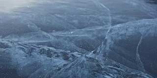 戴手套的人在冰上打碎冰。缓慢的运动。镜头移到了冰的后面。一块美丽的冰在冰的周围裂开，有神奇的裂缝。冰冻水的颗粒。