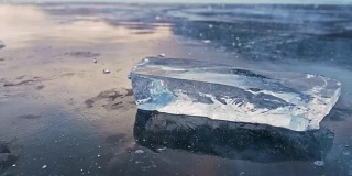 浮冰在冰面上旋转，映衬着令人惊叹的山景。缓慢的运动。镜头移到了冰的后面。冰在冰上旋转，有神奇的裂缝，非常漂亮。